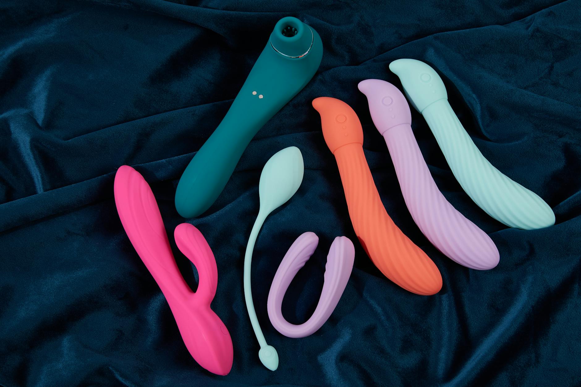 Frau hält nachdenklich zwei farbige Vibratoren in den Händen