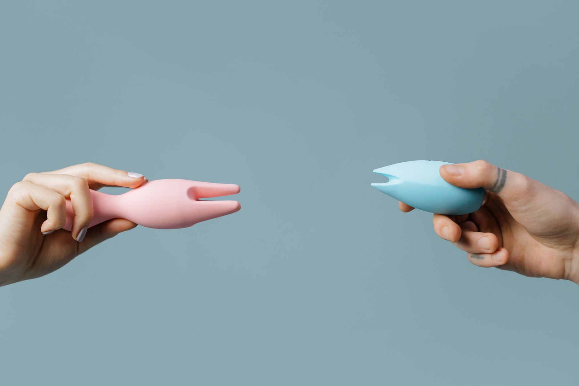 Eine Hand hält einen modernen Vibrator gegen einen minimalistischen Hintergrund