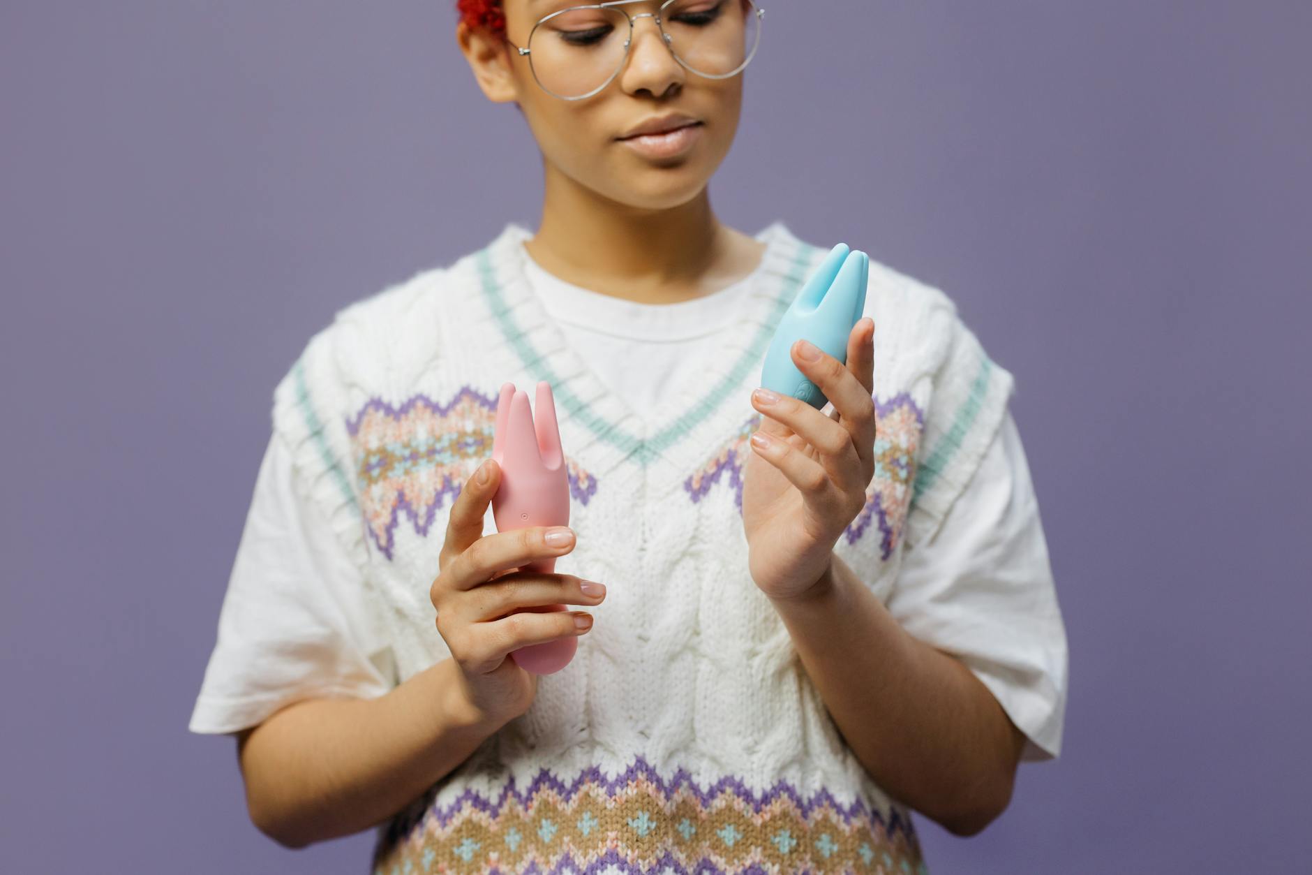 Frau hält blauen und rosa Zitronenvibrator in nachdenklicher Pose